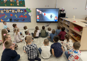 Dzieci oglądają film edukacyjny o tradycjach andrzejkowych.