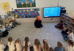 Pani w przebraniu wróżki opowiada dzieciom o Andrzejkach.