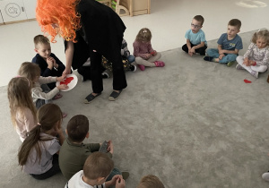 Wróżka rozdaje dzieciom serduszka z imionami.