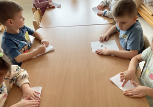 Dzieci składają kartki z kropelką farby.