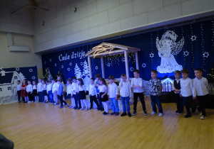 Dzieci w strojach galowych śpiewają piosenkę dla dziadków