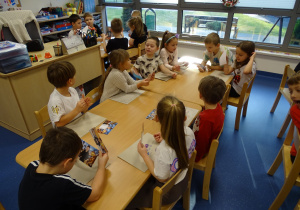 Dzieci oglądają swoje zdjęcia, które będą wklejać do ramki