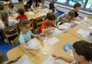 Dzieci przyklejają zdjęcia do podstawki ramki