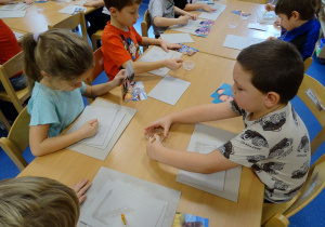 Dzieci przyklejają zdjęcia do podstawki ramki