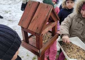 Dzieci sypia ziarno do karmnika