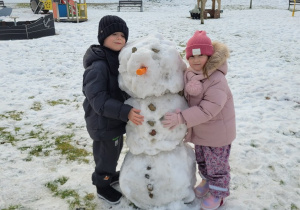 Dzieci przytulają bałwanka