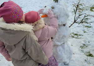 Dzieci upiększaja bałwanka