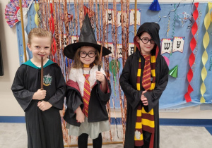 Samek, Pola i Franio w strojach karnawałowych pozują na tle dekoracji