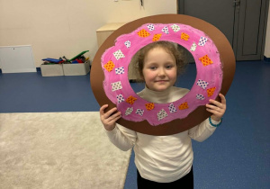 Dziewczynka trzyma ramkę w kształcie pączka