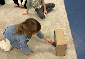 Dziewczynka wrzuca obrazek do pudełka