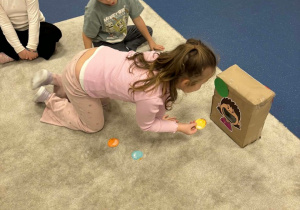 Dziewczynka wrzuca obrazek do pudełka