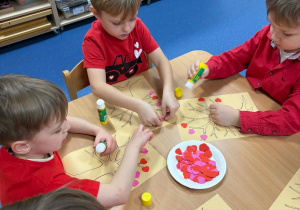 Dzieci wyklejają drzewko serduszkami