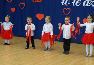 Dzieci wykonują gesty choreograficzne podczas przedstawienia.