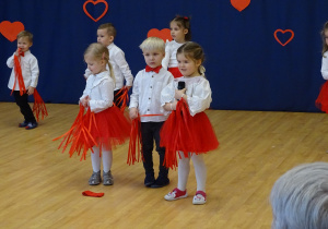 Dzieci ustawione w grupie, jedno trzyma mikrofon podczas występu.