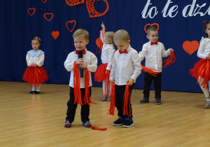 Dwoje dzieci trzyma się za ręce podczas występu.