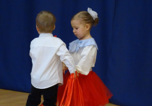 Kilkoro dzieci porusza się po scenie w trakcie układu tanecznego.