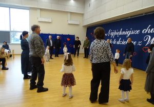 Dzieci i dorośli stoją w kręgu podczas wspólnej zabawy.