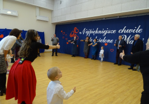 Dorośli i dzieci wykonują gesty w trakcie zabawy.