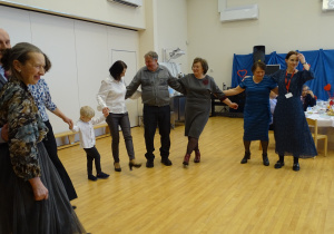 Dorośli i dziecko tańczą, trzymając się za ręce.