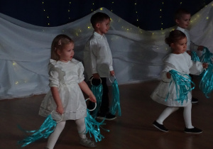 Dzieci idą w szeregu z wstążkami.