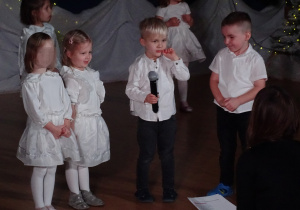 Chłopiec trzyma mikrofon podczas występu.