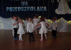 Dzieci stoją w kręgu, trzymając się za ręce.