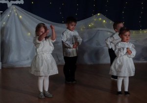 Dzieci wykonują gesty w trakcie występu.