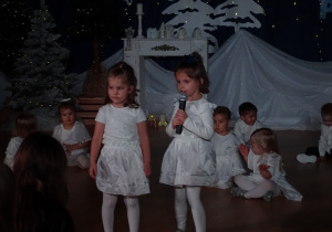 Dziewczynka mówi do mikrofonu na scenie.