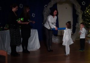 Nauczycielka pasuje dziecko symbolicznym ołówkiem.