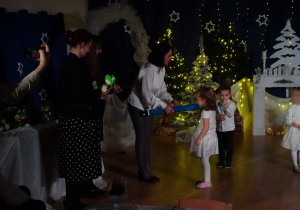 Dziecko odbiera upominek od nauczycielki.