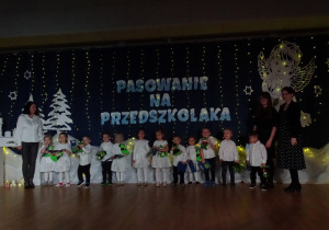Dzieci stoją na scenie z nauczycielkami.