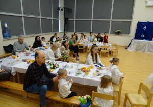 Goście siedzą przy stołach w sali.