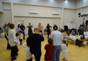 Dzieci i dorośli tańczą w kręgu.