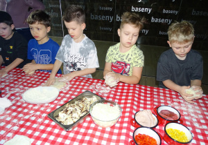 Dzieci rozciągają ciasto na placek