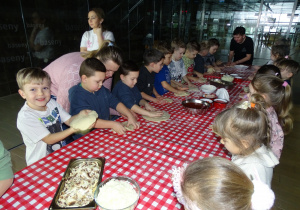Dzieci rozciągają ciasto na placek