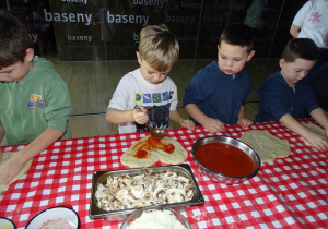 Dzieci smarują pizze sosem