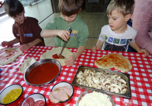 Dzieci smarują pizze sosem