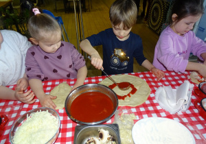 Dzieci smarują sosem pizze