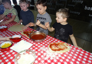 Dzieci układają ulubione dodatki na pizze, smarują sosem