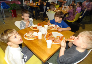 Dzieci zajadają sie pizzą