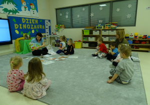 pani pokazuje książkę z dinozaurami