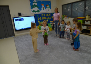 dziewczynki przekazują sobie dinozaura