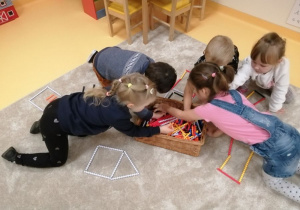 Dzieci podzielona na grupy budują swoje domki z klocków.