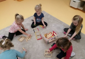Dzieci podzielona na grupy budują swoje domki z klocków.