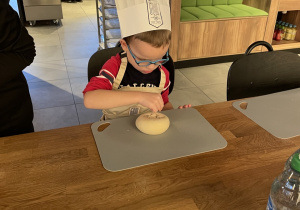 Kuba posypuje bułkę makiem.