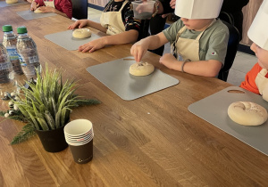 dzieci posypują bułki makiem.