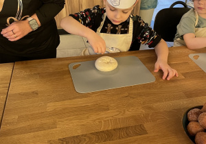 Michał posypuje bułkę makiem.