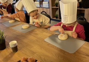 Amelka posypuje bułkę makiem.