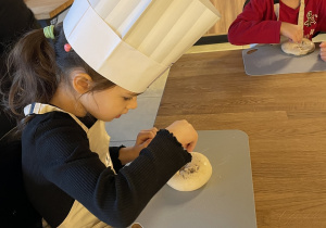 Laura i Adaś posypują swoje bułki makiem.