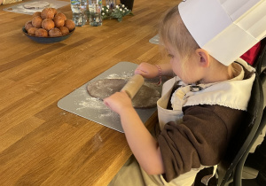 Dzieci wałkują ciasto na pierniczki.